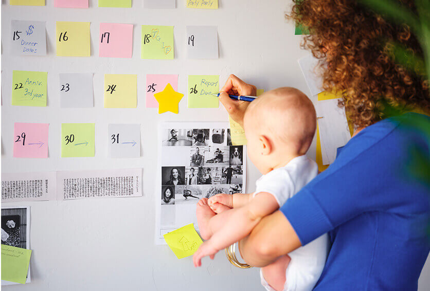 mother holding her baby while marking something on a calendar