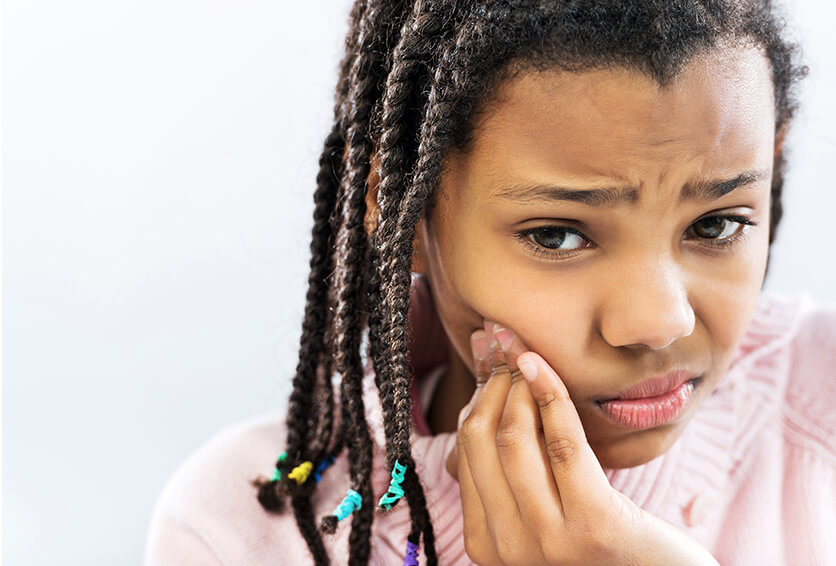 girl holding her jaw in pain