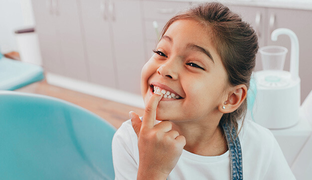 young, smiling girl pointing at her teeth