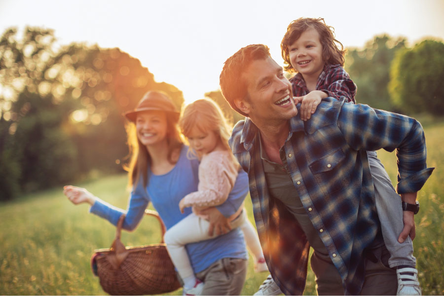 A mom and dad go on a walk outside in nature with their 2 children to have a picnic