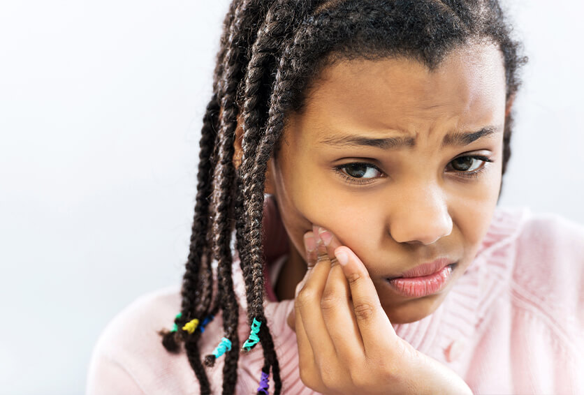 young girl holding her jaw in pain