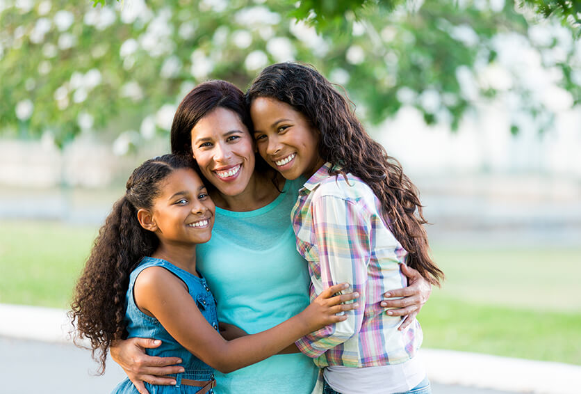 mother hugging her two daughters