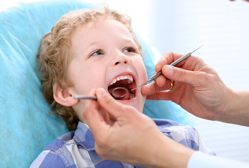 young boy having his teeth examined