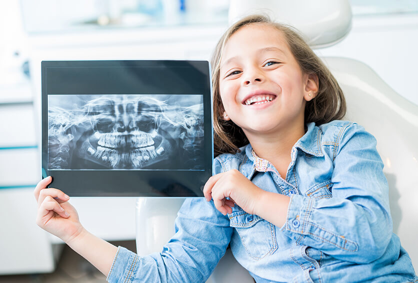 young, smiling girl holding up an x-ray