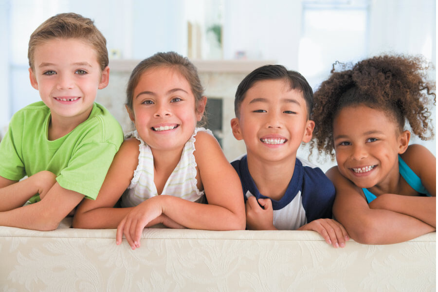 4 children smile while sitting on a couch