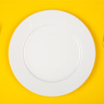 Aerial view of a white plate against a yellow background to symbolize a child's nutrition