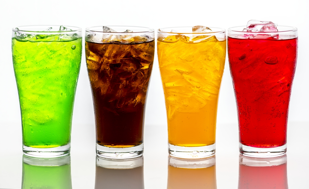 A green, brown, orange, and red soda in glasses with ice